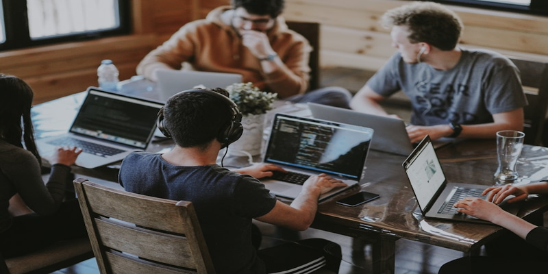 Group of professionals collaborating on laptops in a workspace, illustrating teamwork in custom software development projects.